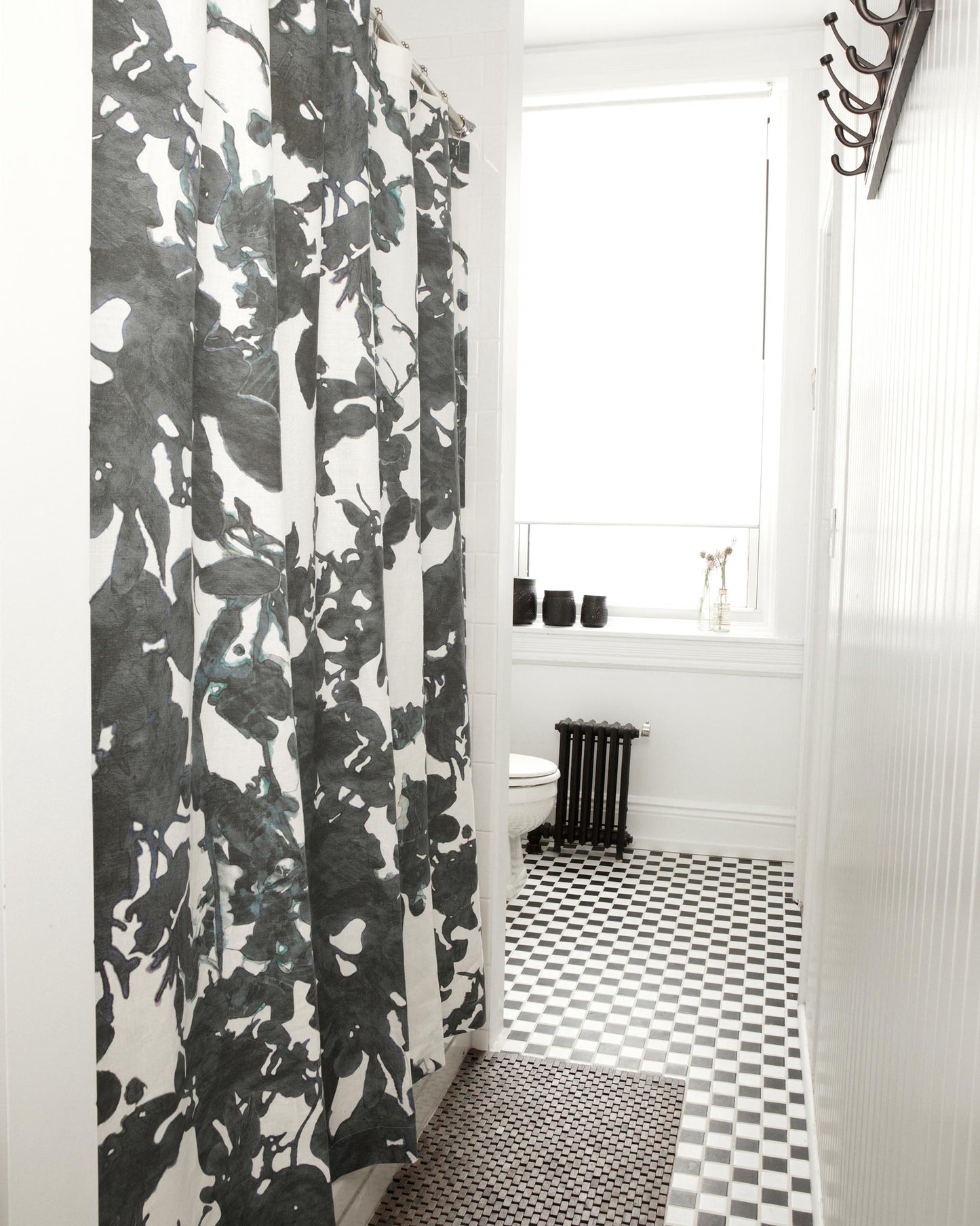 A black and white bathroom with a Up For Anything Fabric watercolor shower curtain.