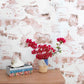 A vase of flowers on a table in front of the Out East Paperweave Shell wallcovering