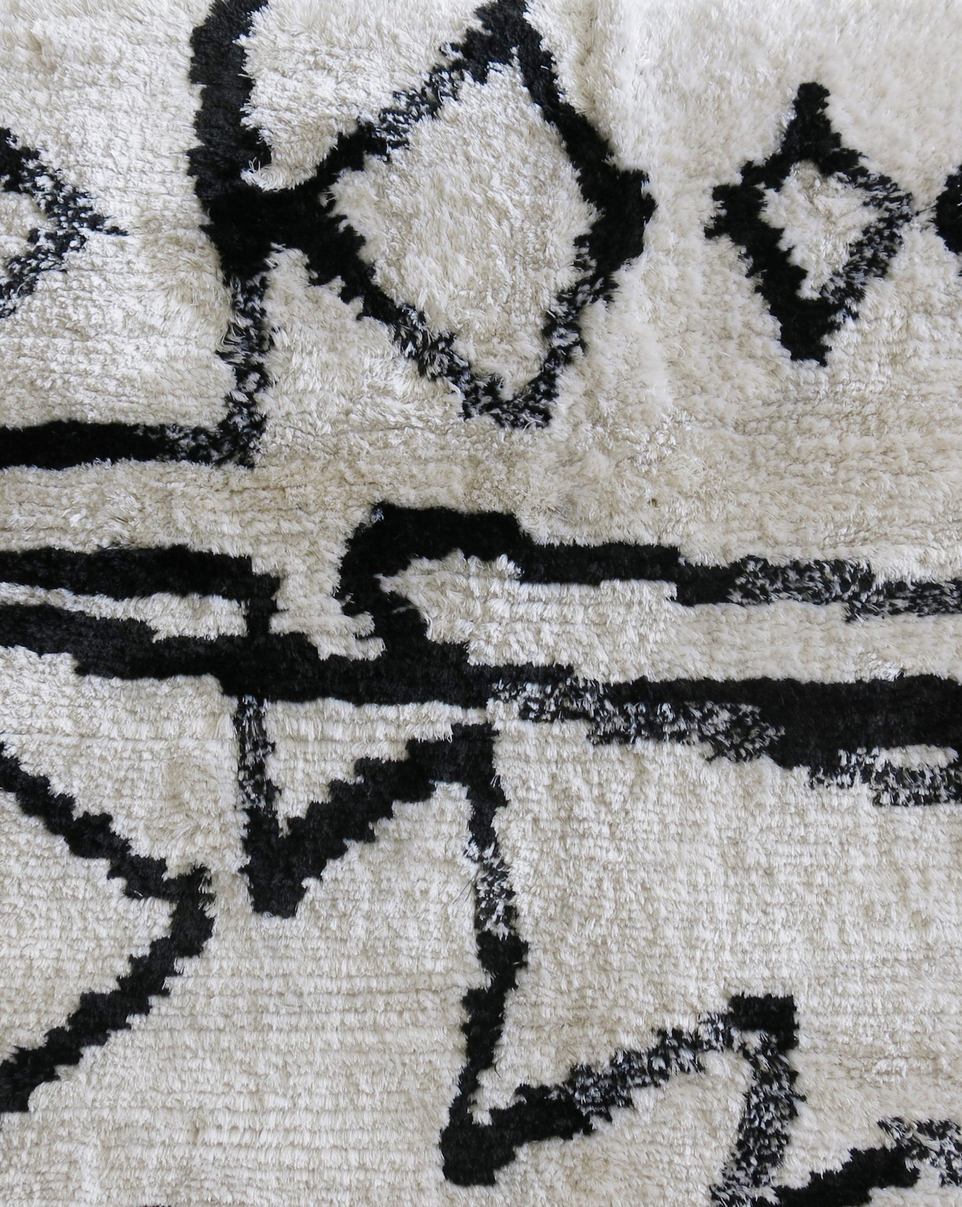 An Akimbo Hand Knotted Rug||Black And White with graphic geometric designs on it.