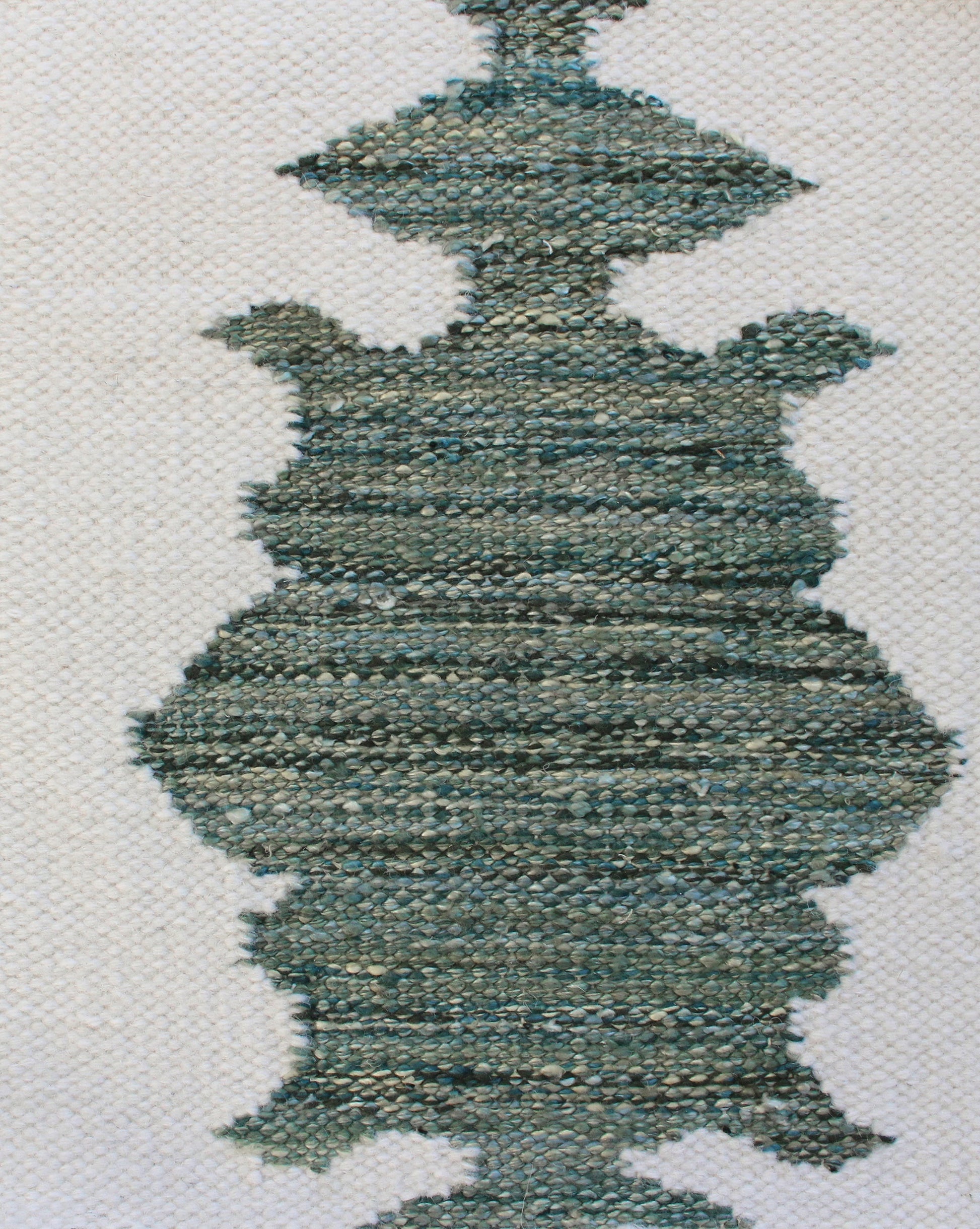 A close up of a blue and white woven pillow featuring the Areca Palms Flatweave Rug Chloros colorway
