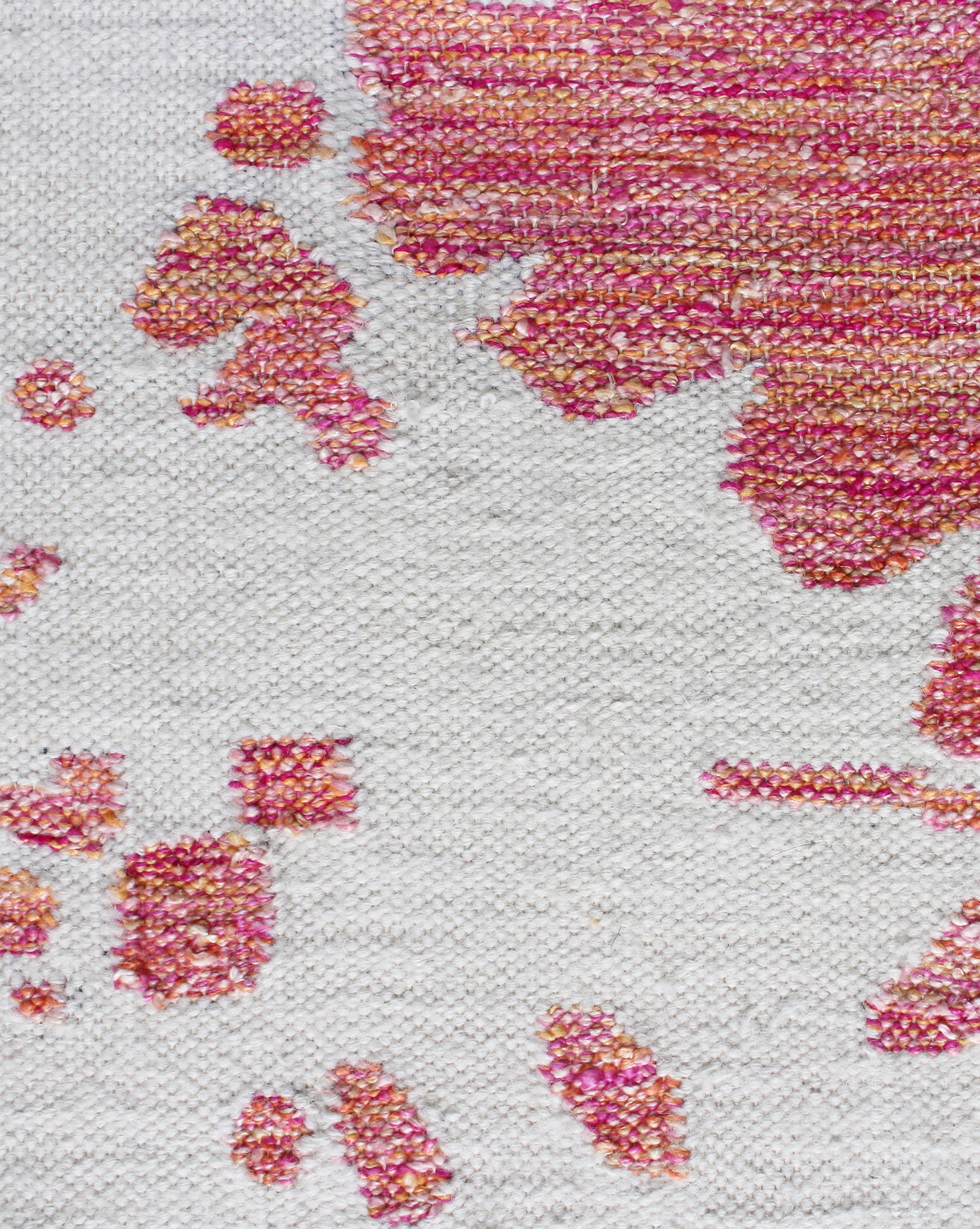 A close up of a durable Nairutya Flatweave Rug Raspberry from the Jangala Collection with pink and white splatters