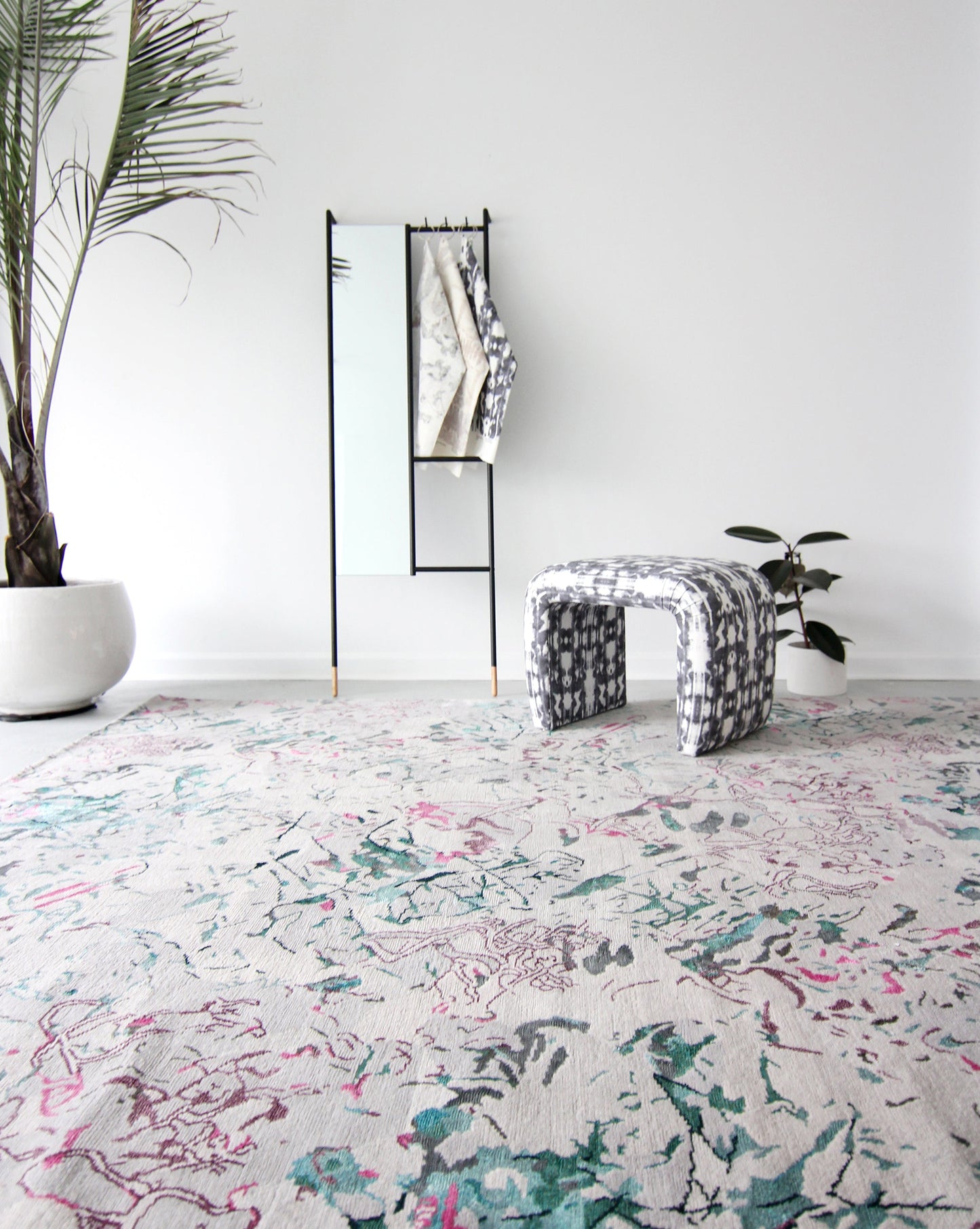 A white room with a Bosky Toile Hand Knotted Rug Spectra and a plant on it