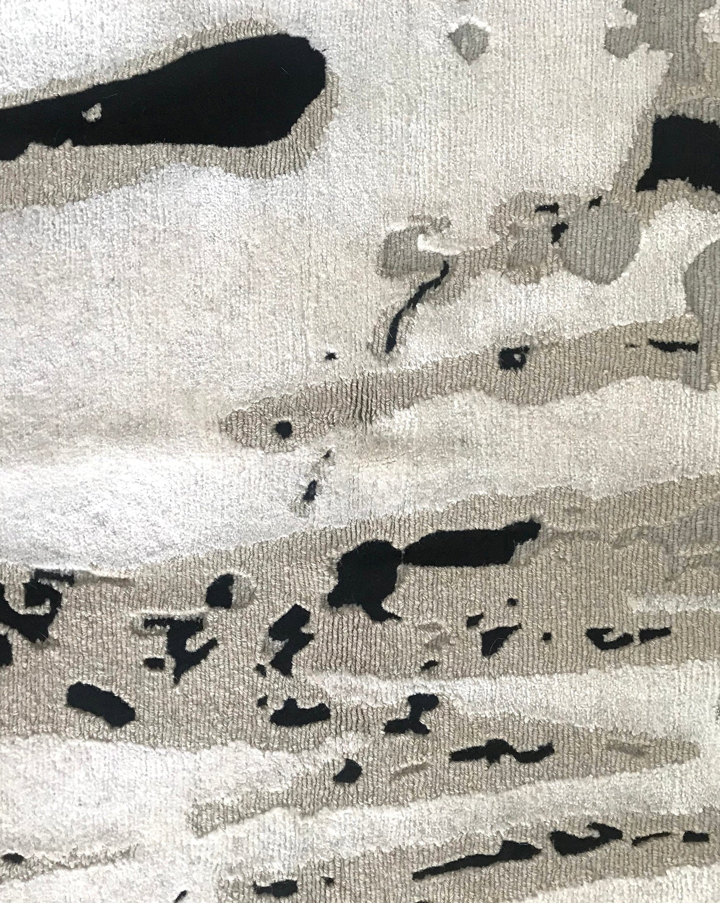 A close up of a Linea Hand Knotted Rug Black And Beige with black and white splatters