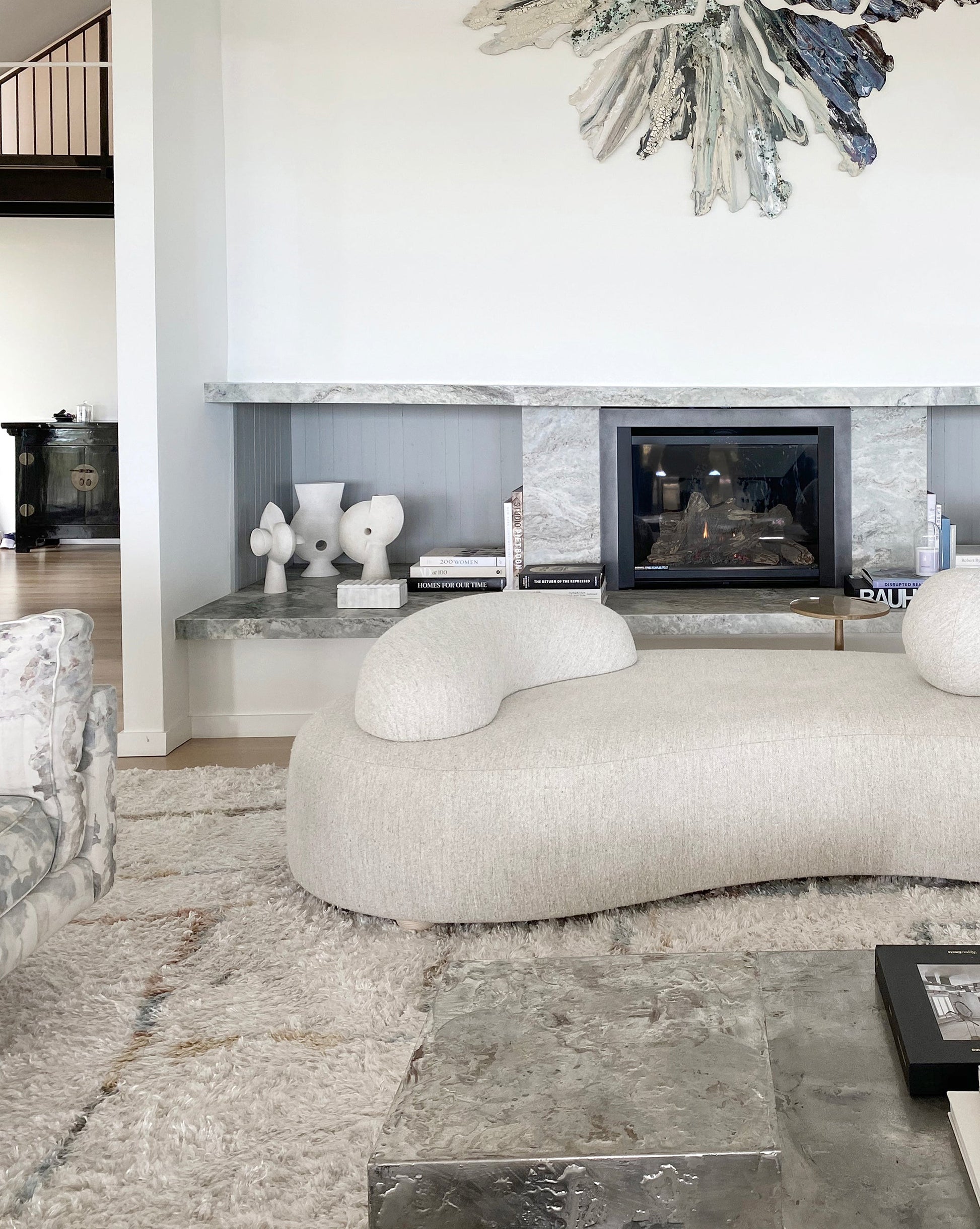 A living room with a white couch and a fireplace, featuring a Portico Hand Knotted Rug||Sol.