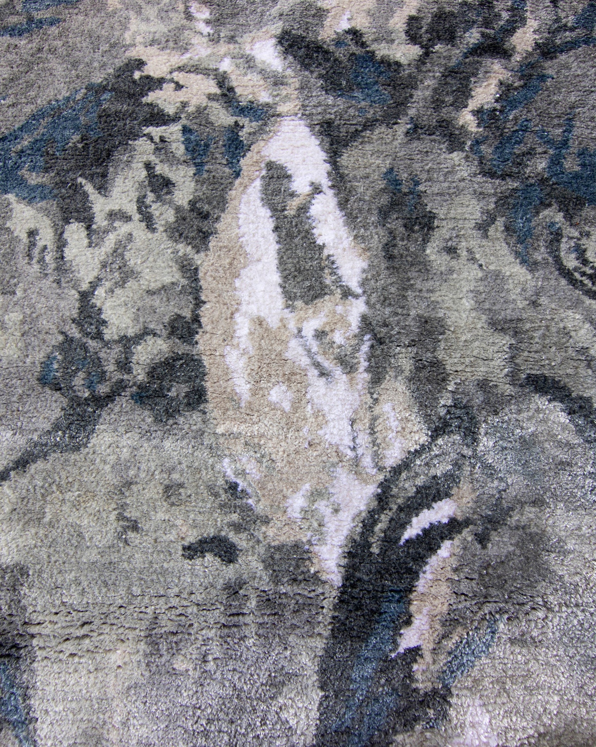 A close up image of Palmeti Hand Knotted Rug Notte featuring shades of grey and blue