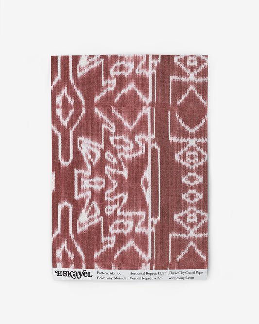 A red and white Akimbo Wallpaper Sample||Morinda Ikat pattern on a piece of cloth sample.