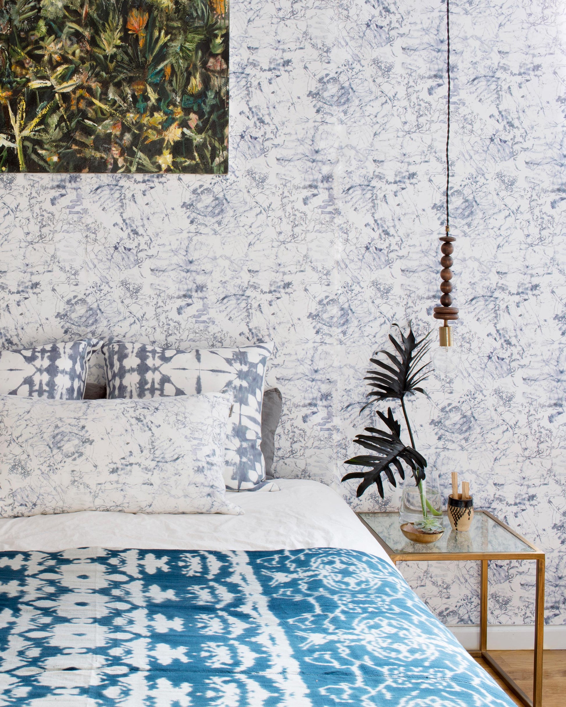 A luxury bed with a blue and white Bosky Toile Wallpaper||Midnight pattern on it.