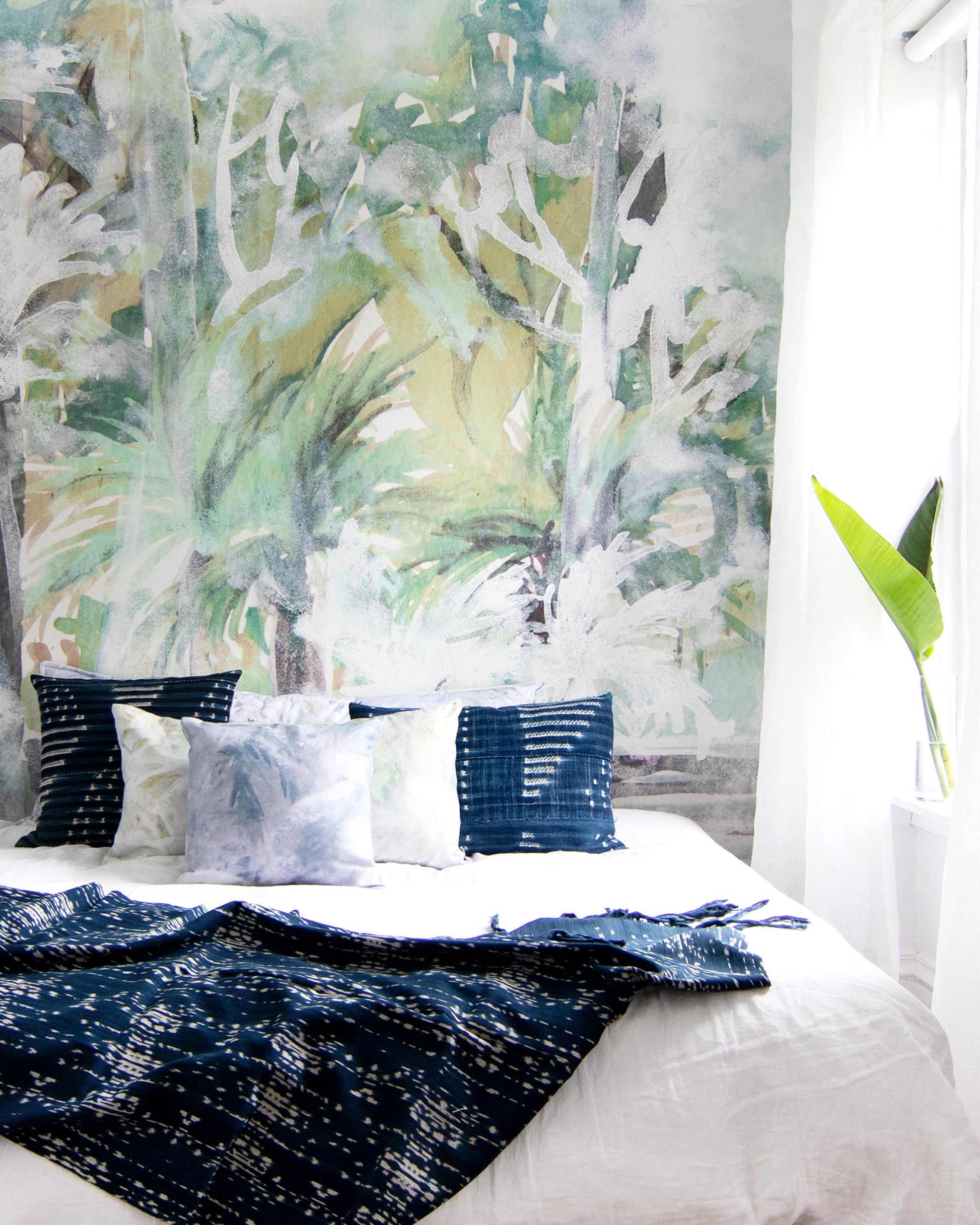 A bedroom with a large mural, Regalo di Dio Wallpaper Mural Verde, on the wall.
