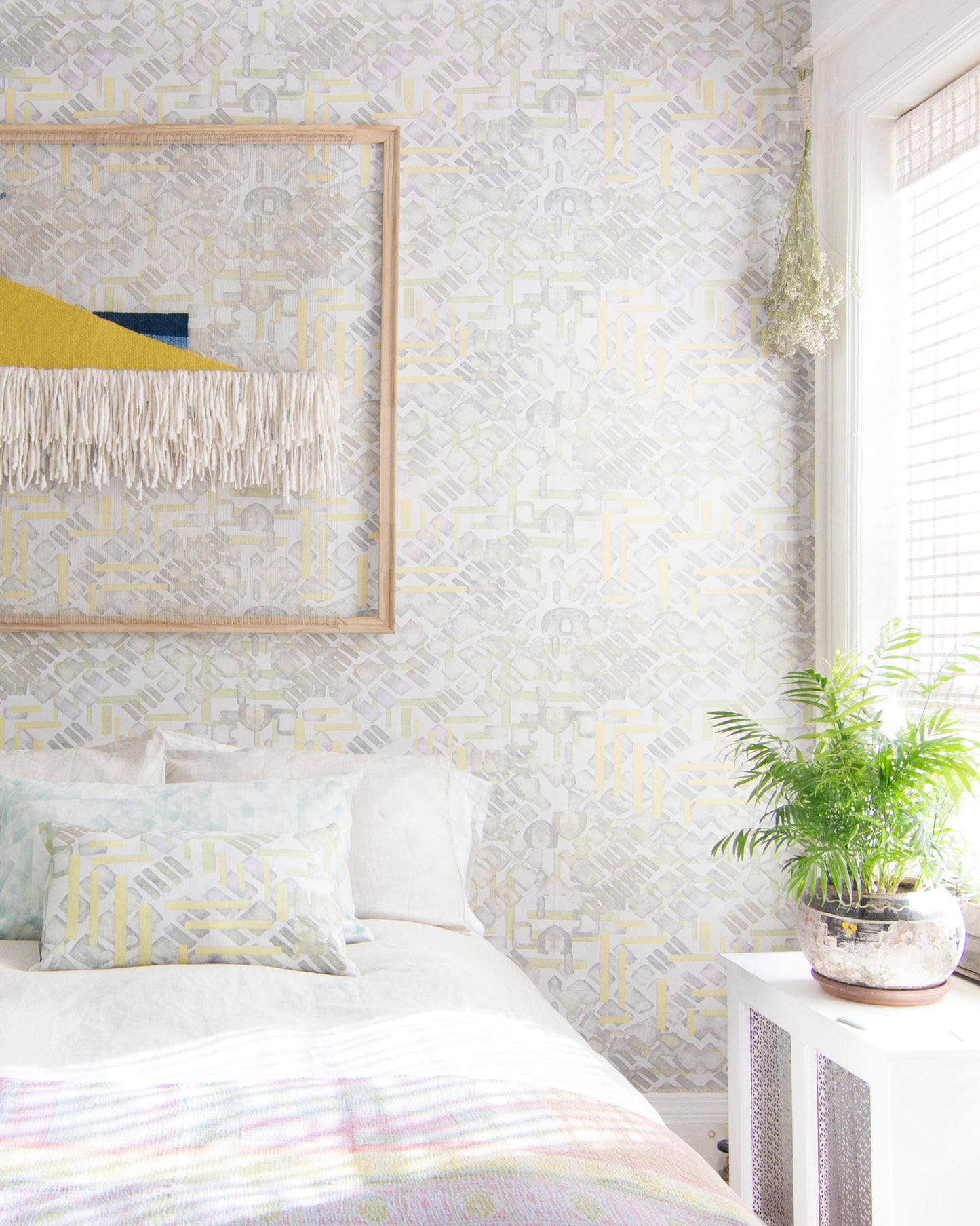 A bed in a room with Stele Wallpaper Citrus patterned fabric