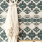 A white dress hangs on a wall in front of The Dance Wallpaper Olive