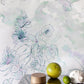 A green apple is sitting on a table in front of Belize Blooms Wallpaper