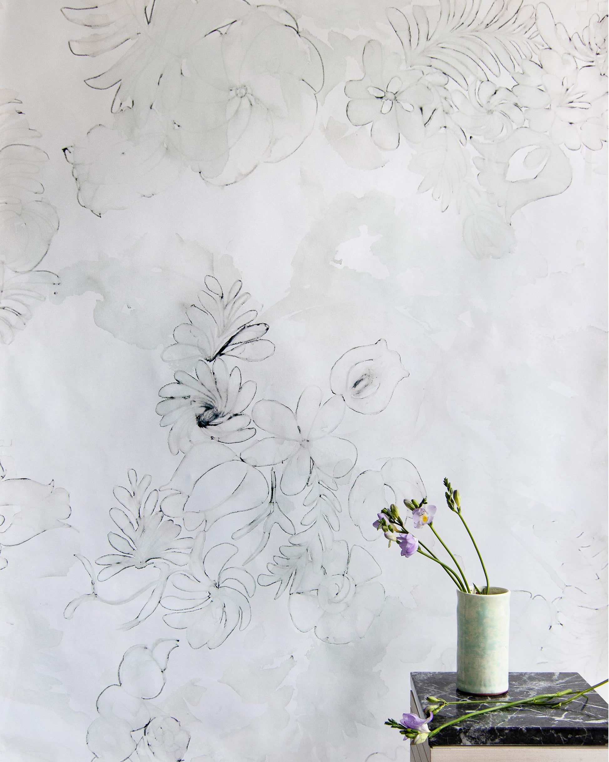 A vase of Belize Blooms Wallpaper sits on a table in front of a wall