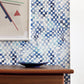 A blue and white Chess Wallpaper Ocean tiled wall behind a dresser