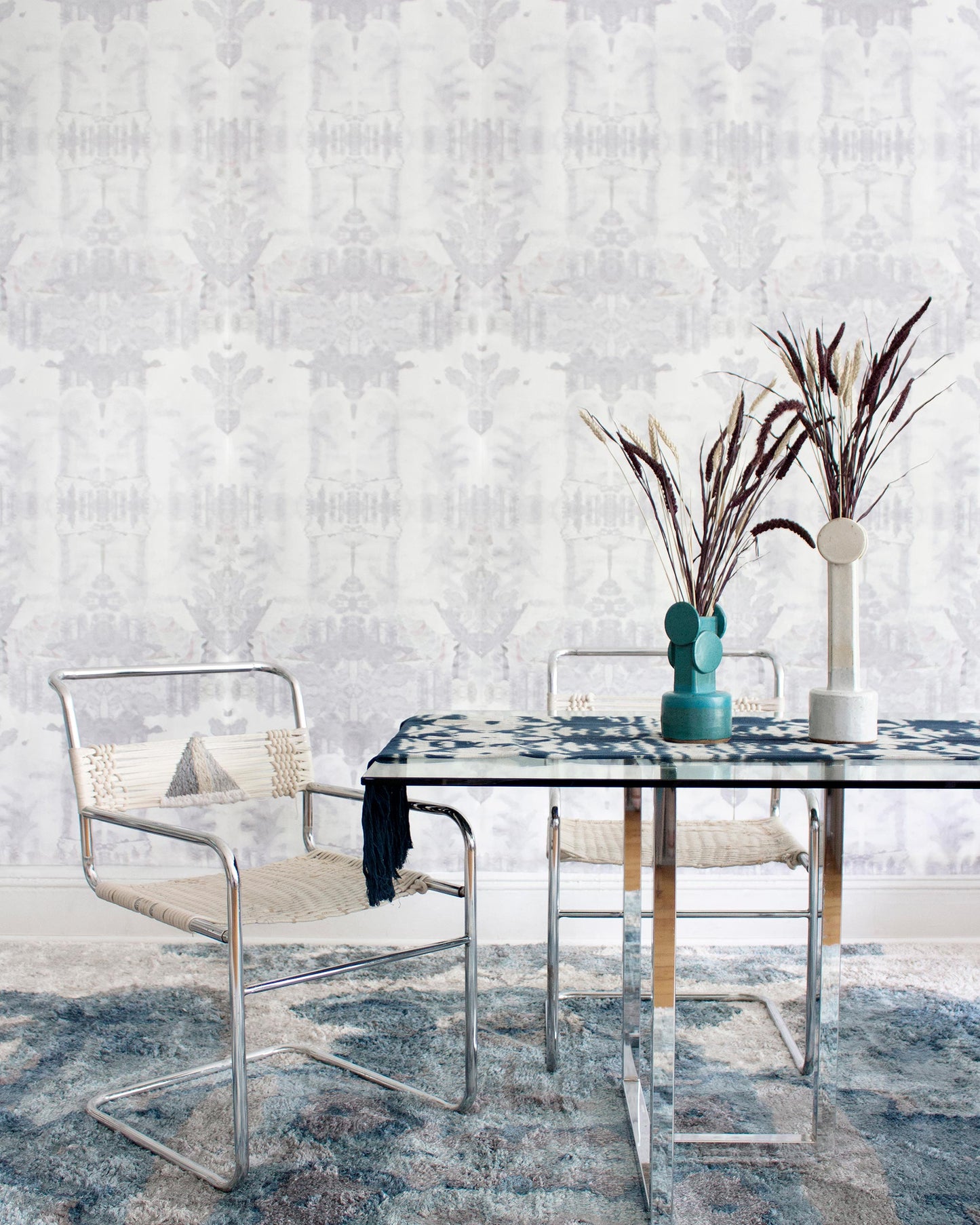 A dining room with a table and chairs in front of Clairmont Wallpaper||Ash.