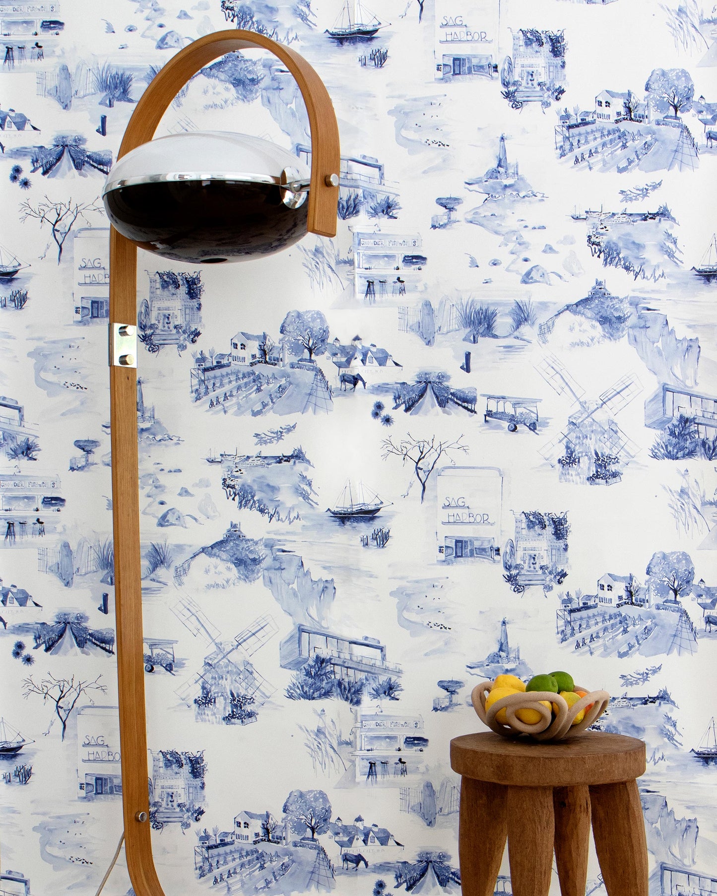 A blue and white Out East Wallpaper Cobalt pattern fabric in front of a wooden stool