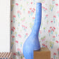 A blue vase sits on a wooden table in front of Perfect Palm Wallpaper Polychrome wallpaper