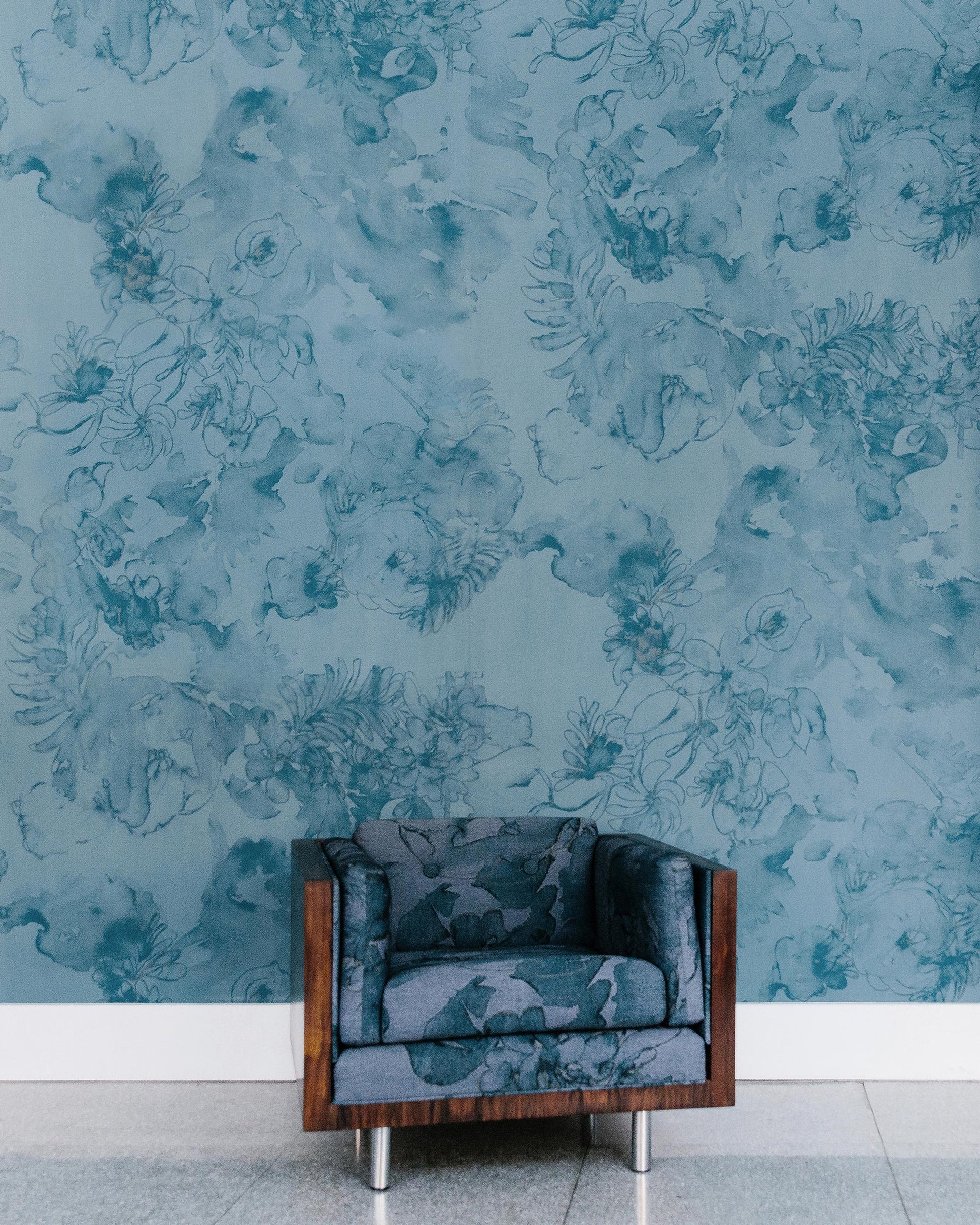 A blue chair in front of a luxury Belize Blooms Wallpaper Aquamarine