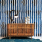 A blue striped Bold Stripe Wallpaper Azure in front of a blue dresser
