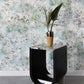 A small table with a plant on it in front of a custom Cortile Wallpaper Verde