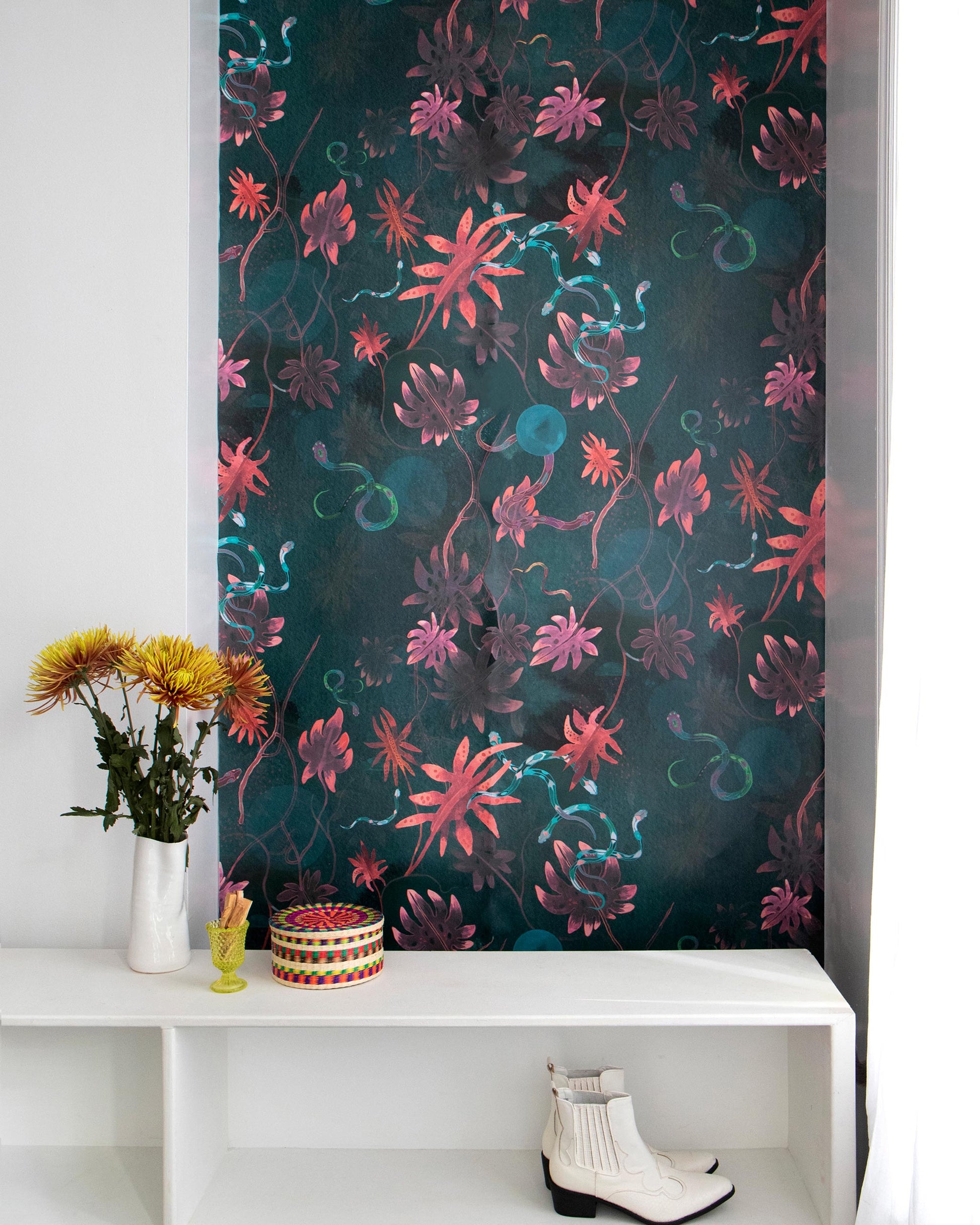 A white shelf with a vase filled with Edera Wallpaper on it, next to a wall adorned with a chinoiserie-inspired floral pattern