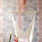 A hanging chair in a room with a pink Laurel Forest Wallpaper Persimmon wall panel