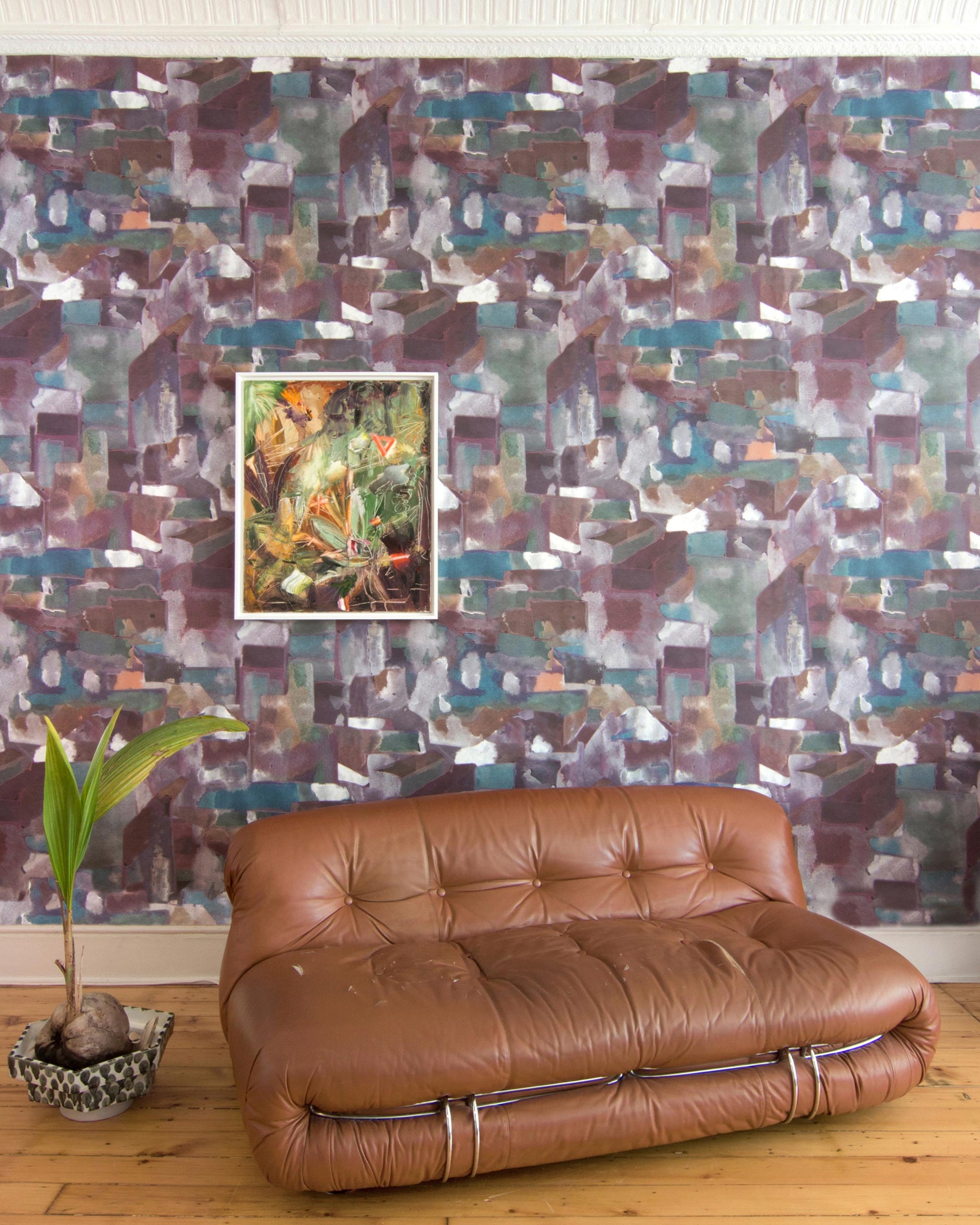 A brown leather couch in front of a Medina Wallpaper wall