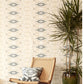 A chair and a potted plant in front of The Knitting Wallpaper Sand luxury wallpaper