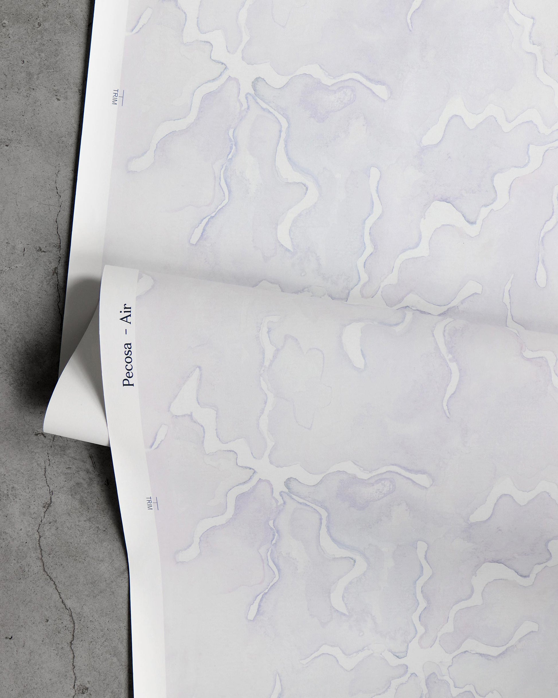 A purple pattern on a white sheet of Pecosa Wallpaper with sun motifs