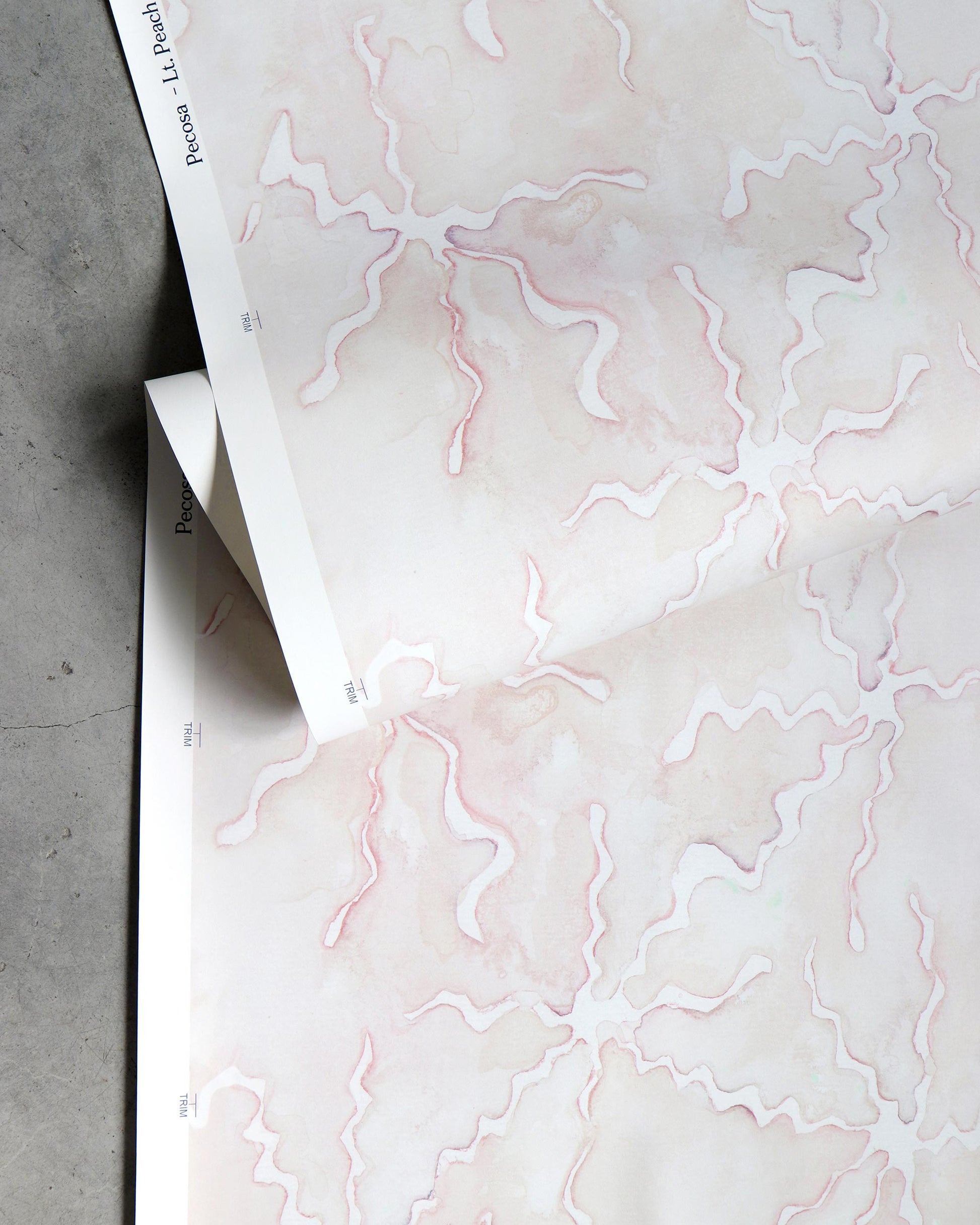 A pink and white patterned Pecosa Wallpaper Light Peach sheet with a resist dye technique