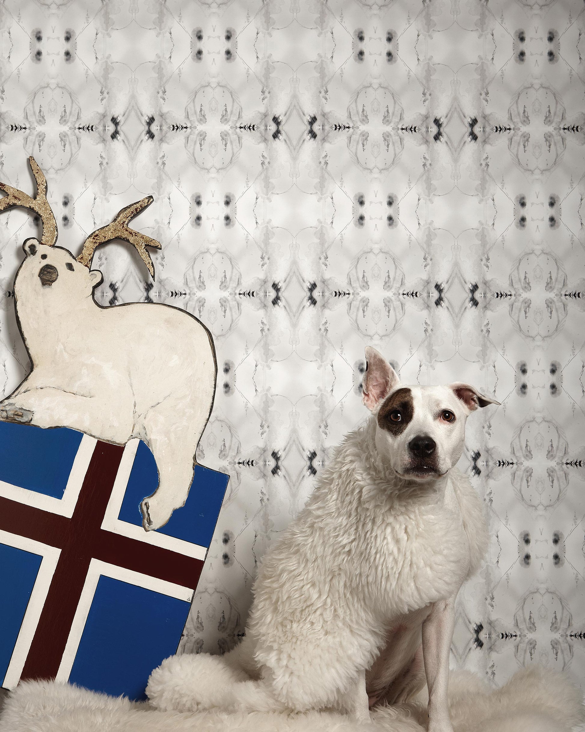 A dog is sitting next to a reindeer and a Polar Pedigree Wallpaper in greyscale