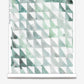 A roll of wallpaper with green and white triangles, Triangle Checks Wallwallpaper, Verde, on it