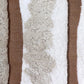 A row of Bold Stripe Hand Knotted Rug Sandstone sheepskin pillows on a brown background