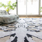 A Mamoun Hand Knotted Rug Neutral with a symmetrical abstract design in a room with a window