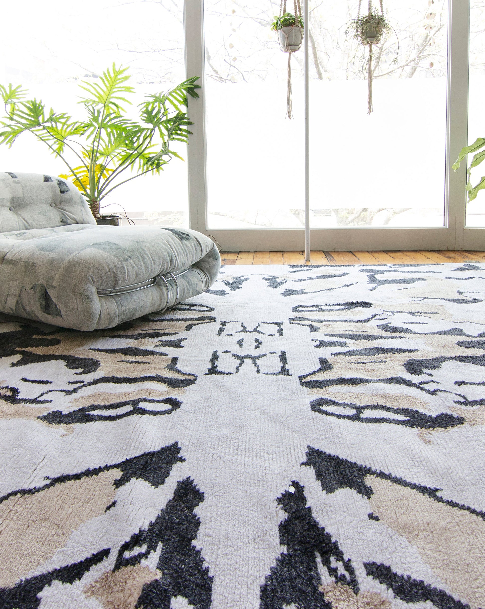 A Mamoun Hand Knotted Rug Neutral with a symmetrical abstract design in a room with a window